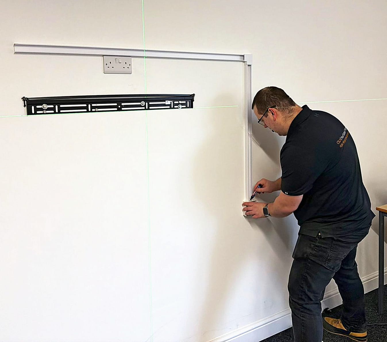 Csln Group Engineer Marking Up A Wall-Mounted Display Bracket Using A Cross-Line Laser Level During An Office Av Installation